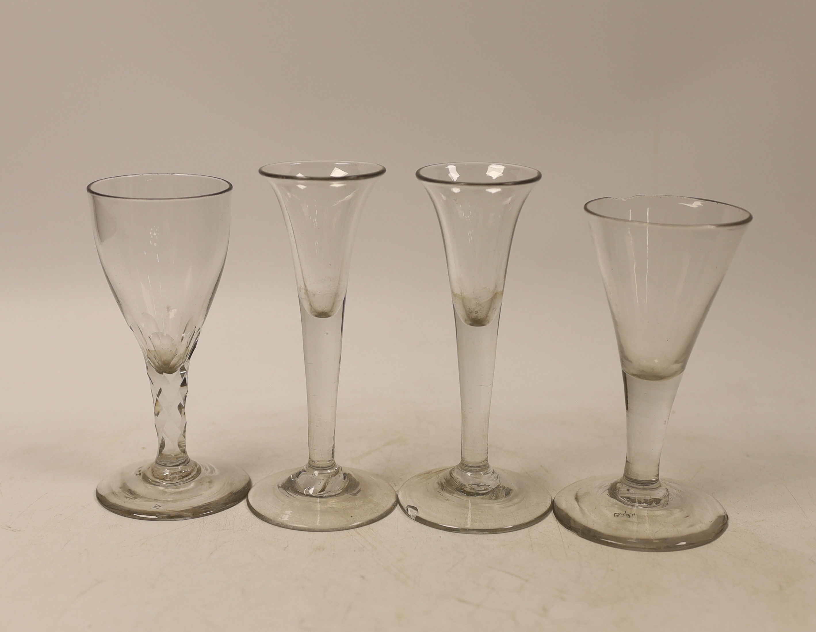 Three mid-18th century drawn trumpet drinking glasses, and a facet stem glass, tallest 13cm (4)